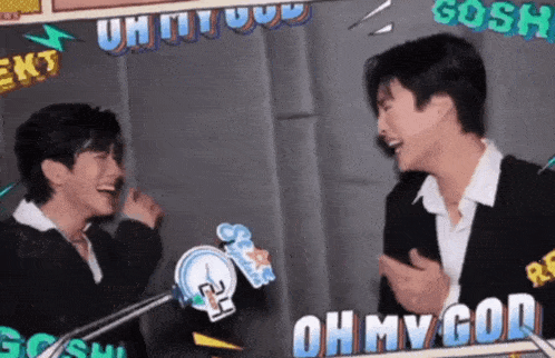 two men are laughing in front of a sign that says ' oh my god '