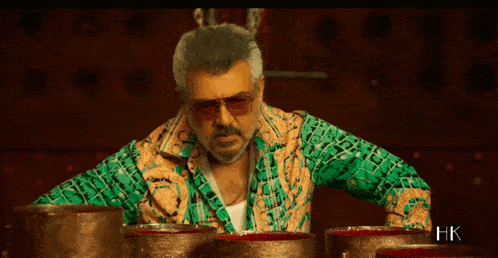 a man wearing sunglasses and a green shirt is standing in front of a row of bowls of blood .