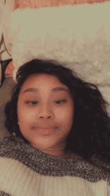 a girl is laying on a bed wearing a sweater