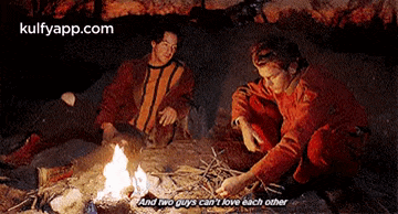 two men are sitting around a campfire with a caption that says " and two guys can 't love each other " .