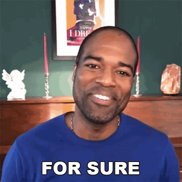 a man in a blue shirt is smiling and says " for sure "