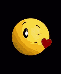 a yellow smiley face is blowing a kiss with a heart in its mouth .