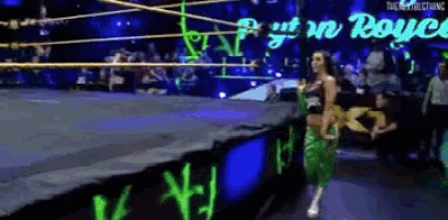 a woman in a green outfit is walking in a wrestling ring with a sign that says royal rumble
