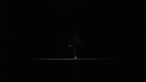 a man is sitting in a dark room with a light coming out of the window .