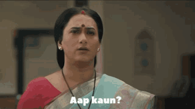 a woman in a red top and a blue saree is asking a question .
