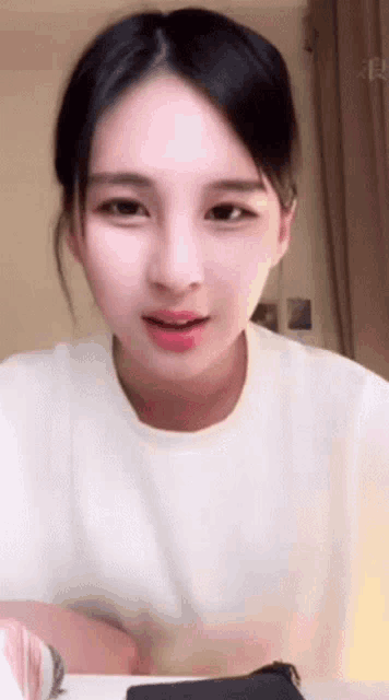 a woman in a white shirt is smiling and looking at the camera