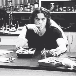 a man in a black shirt is sitting at a table with a tray of food .