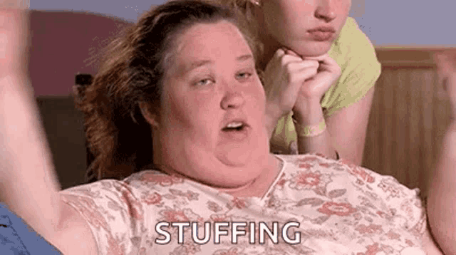 a woman is laying on a bed with her arms in the air and the word stuffing written on her face .