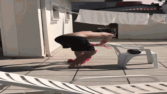 a shirtless man is laying on a patio next to a white chair