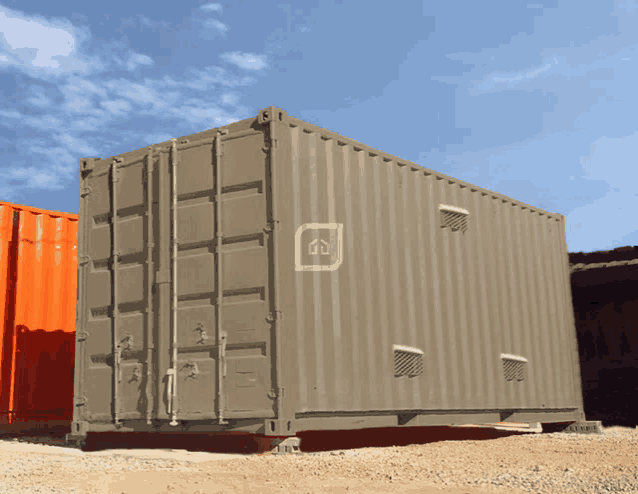 an orange shipping container is next to a gray one