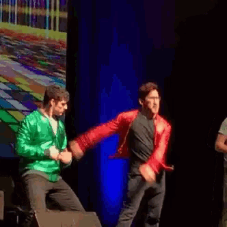 a man in a red jacket is dancing on stage .