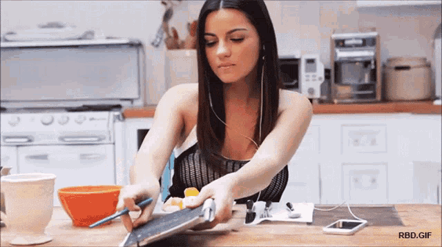 a woman sitting at a table with a tablet and a cell phone with the url rbd.gif below her