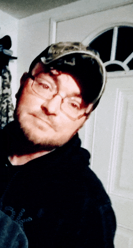 a man wearing glasses and a hat is standing in a doorway