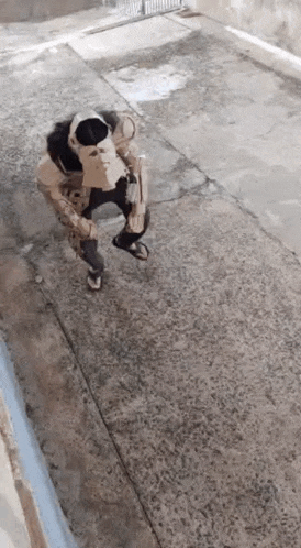 a person wearing a mask is kneeling on the sidewalk .