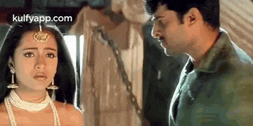 a man and a woman are standing next to each other in a room and looking at each other .