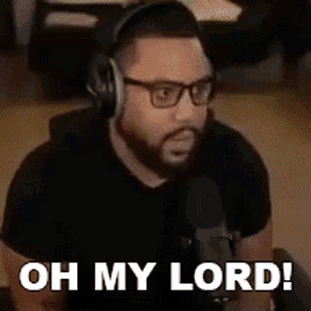 a man with glasses and headphones is sitting in front of a microphone and saying `` oh my lord '' .