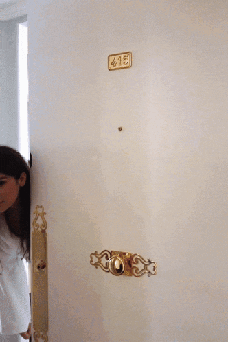 a woman in a white robe stands in front of a door with the number 415 on it