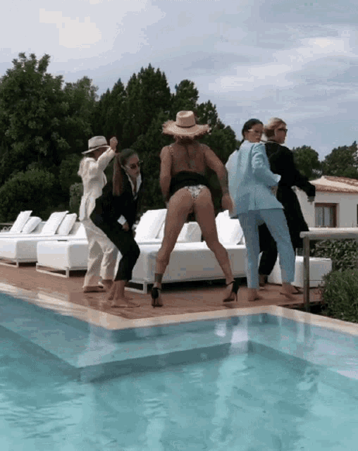 a group of people are dancing by a pool