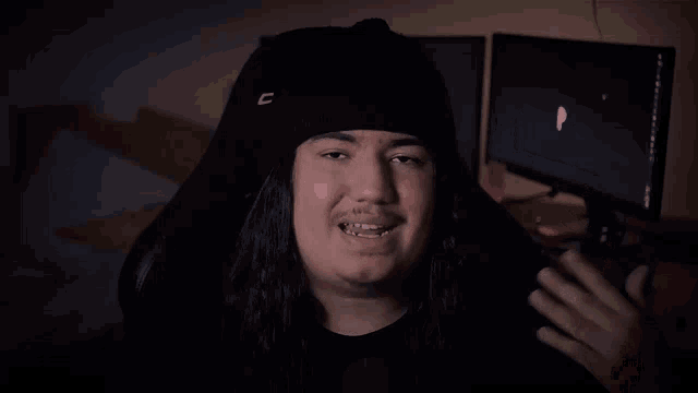 a man with long hair is wearing a black beanie with the letter d on it