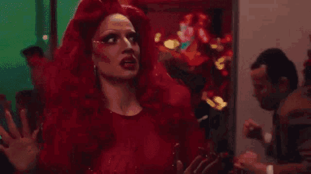 a woman in a red wig is dancing in a room with a man in a suit .