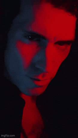 a close up of a man 's face with red and blue light behind him
