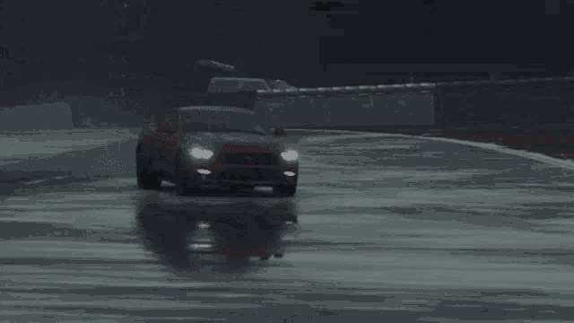 a red mustang is driving down a wet road