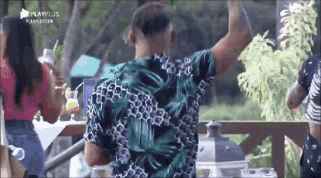 a man in a green shirt is standing with his arms in the air .
