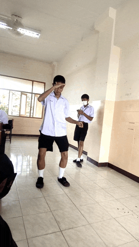 a boy wearing a mask stands in a classroom