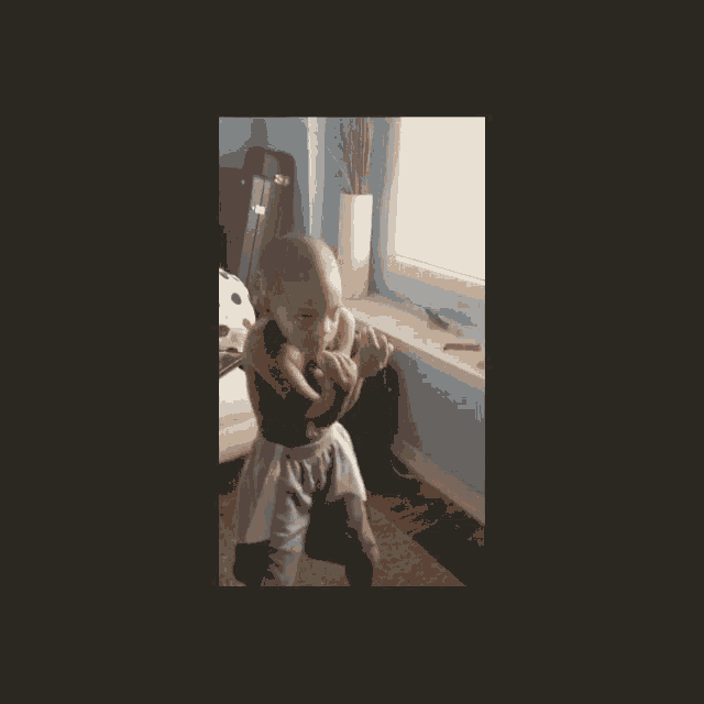 a little girl is standing in a room with a suitcase on the window sill