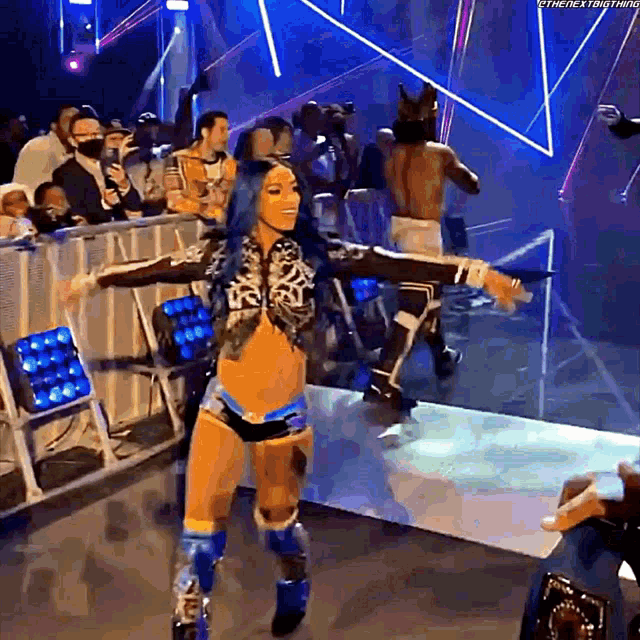 a female wrestler is walking down a ramp with her arms outstretched in front of a crowd .