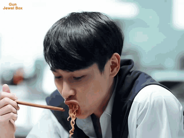 a young man is eating noodles with chopsticks and the words gun jewel box are on the bottom