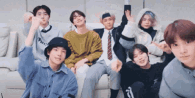 a group of young people are sitting on a couch and making funny faces .