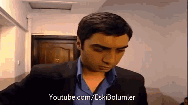 a man in a suit and blue shirt is standing in front of a door in a living room .