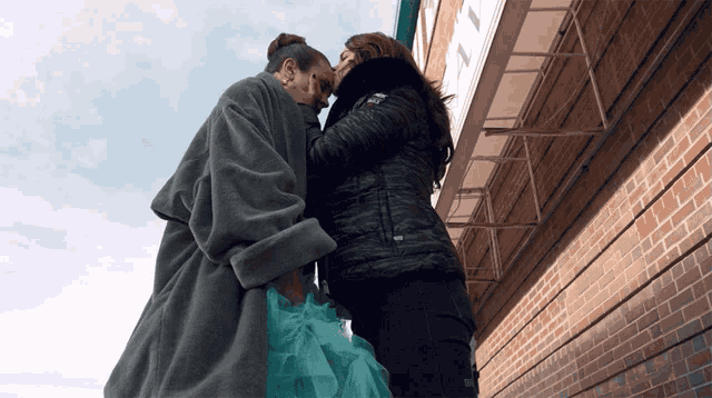 two women hugging each other in front of a building