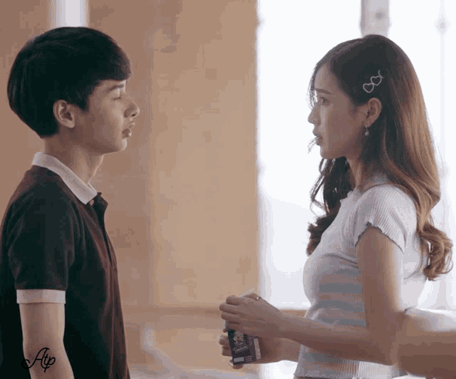 a boy and a girl are looking at each other and the girl is holding a box of grape drink