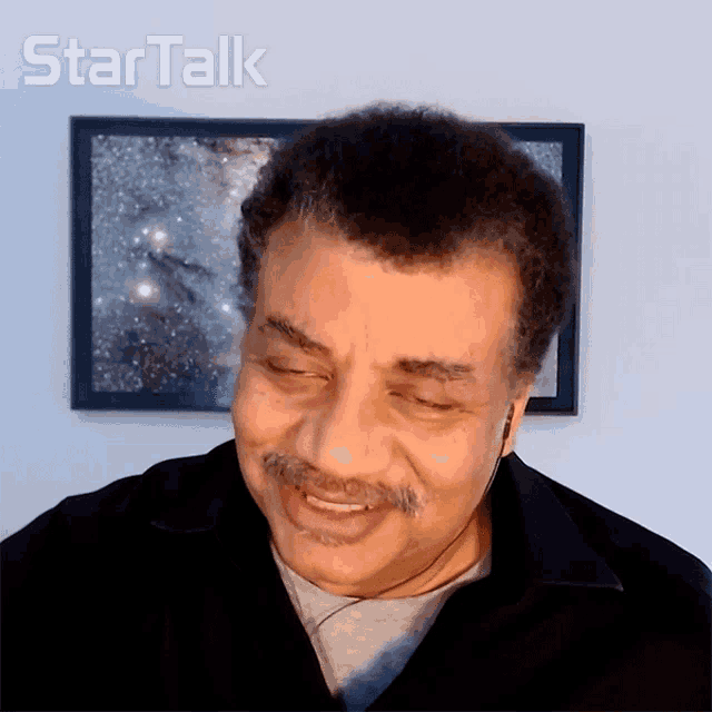 a man is smiling in front of a framed picture that says star talk on it