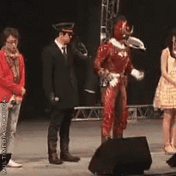 a man in a red costume is standing in front of a microphone on stage