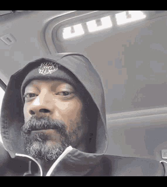 a man with a beard wearing a hoodie and a beanie with the word snoop dogg on it