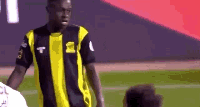 a soccer player wearing a black and yellow striped jersey with the letter t on it