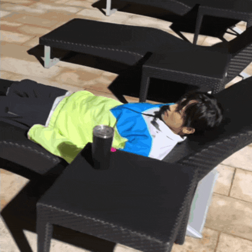 a person laying on a lounge chair with a cup of water