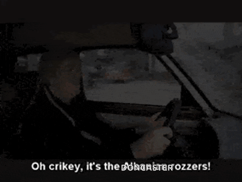 a man is driving a car and looking at his phone .
