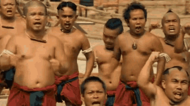 a group of men without shirts are standing next to each other .