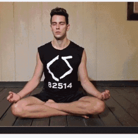 a man is sitting in a lotus position with his eyes closed and wearing a shirt that says 82514