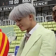 a man in a green suit and tie is standing in a stadium .