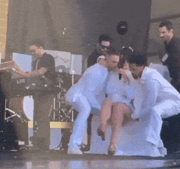 a man in a white suit is holding a woman in a white dress