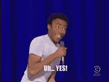a man is holding a microphone in front of a blue curtain and saying yes .