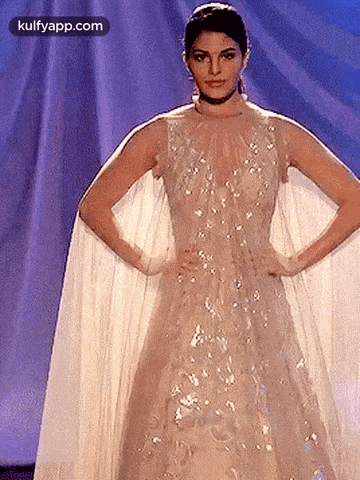 a woman is walking down a runway wearing a white dress .