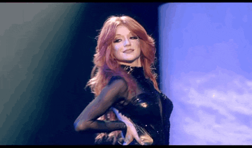 a woman with red hair is dancing on a stage