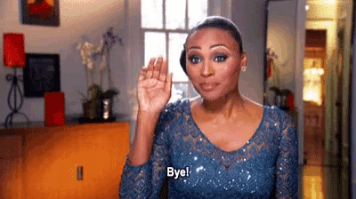 a woman in a blue dress is waving her hand and says bye .