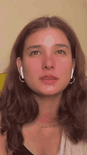 a close up of a woman 's face with earrings and a necklace